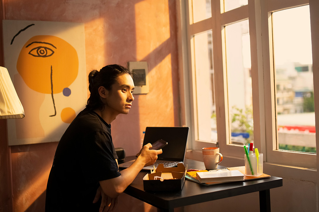 625d063775115f904c817e36_fwa_hero Article Banner Image - A photo of a man looking outside the window while working from home